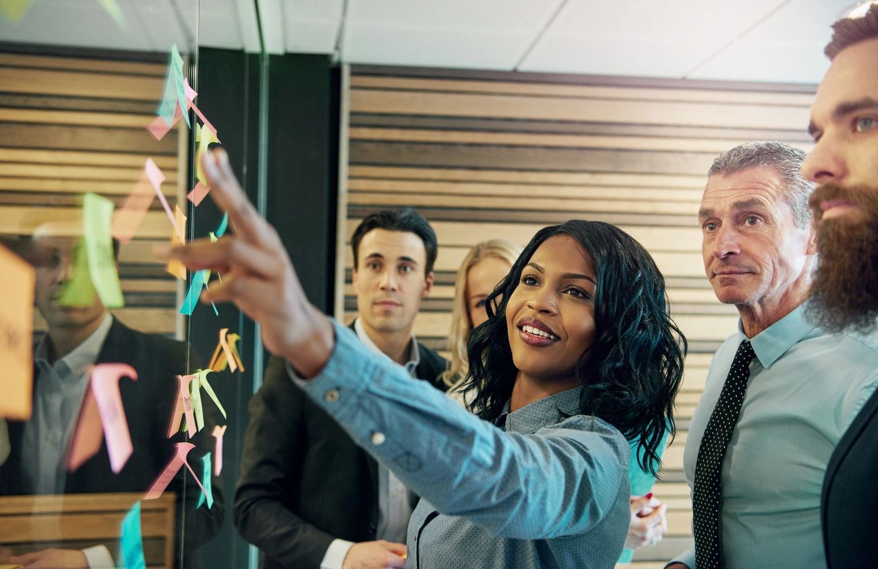 A black woman pointing at a sticky note